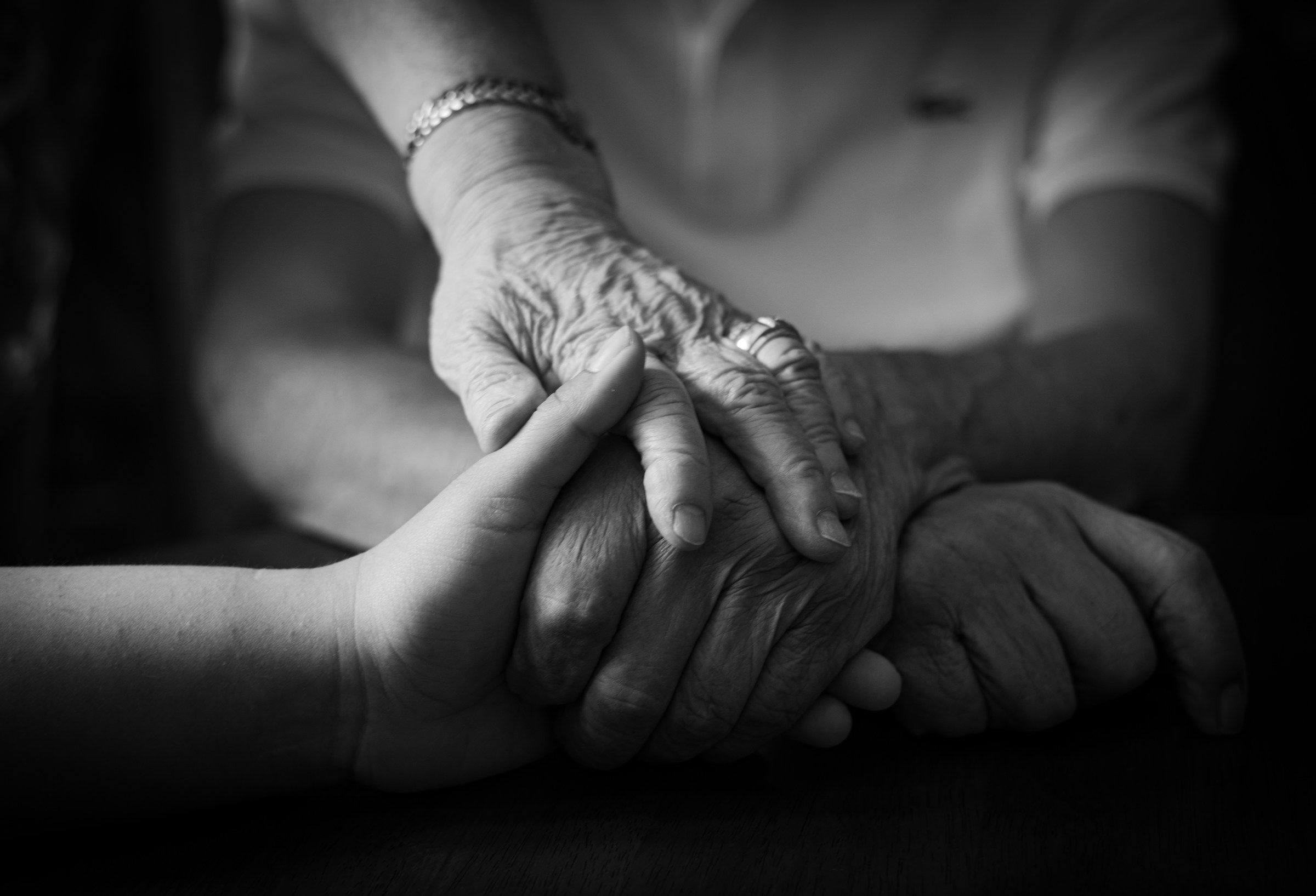 Mãos entrelaçadas em um gesto de cuidado entre gerações